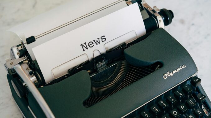 Close-up of an antique typewriter with 'News' on paper.