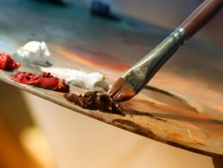 Vibrant artist palette with paint and brush creating colorful artwork.