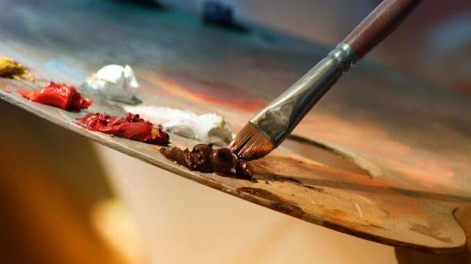 Vibrant artist palette with paint and brush creating colorful artwork.