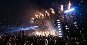 Vibrant concert scene with crowd enjoying night festival and dynamic stage fireworks.