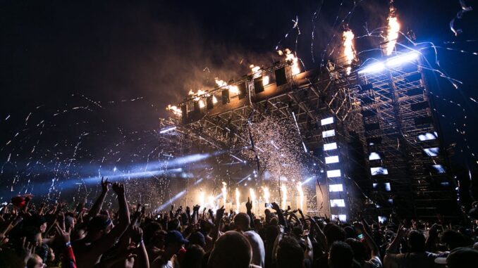 Vibrant concert scene with crowd enjoying night festival and dynamic stage fireworks.