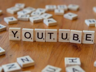 Wooden letter tiles spelling 'YOUTUBE' on a wooden surface, symbolizing video sharing and streaming.