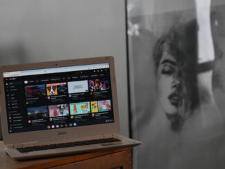 A cozy indoor setting with an Acer laptop displaying YouTube on a wooden table beside artwork.