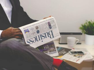 Businessman reading a financial newspaper at a desk, highlighting finance and commerce theme.