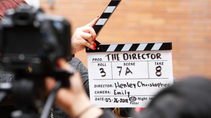 Close-up of film clapperboard in action with camera filming a take on set.