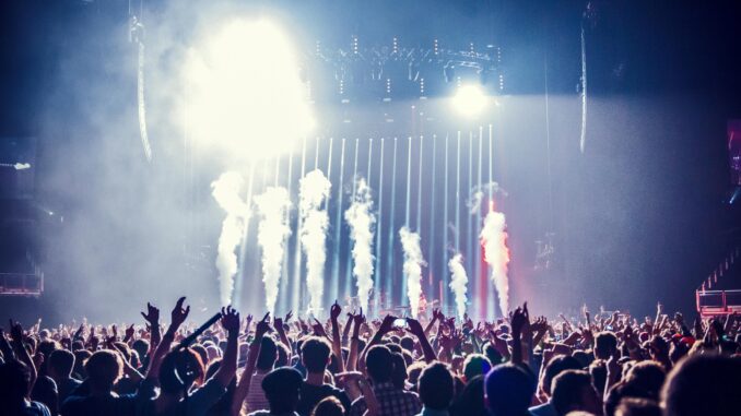 Vibrant concert scene with cheering crowd and bright stage lights creating an electric atmosphere.
