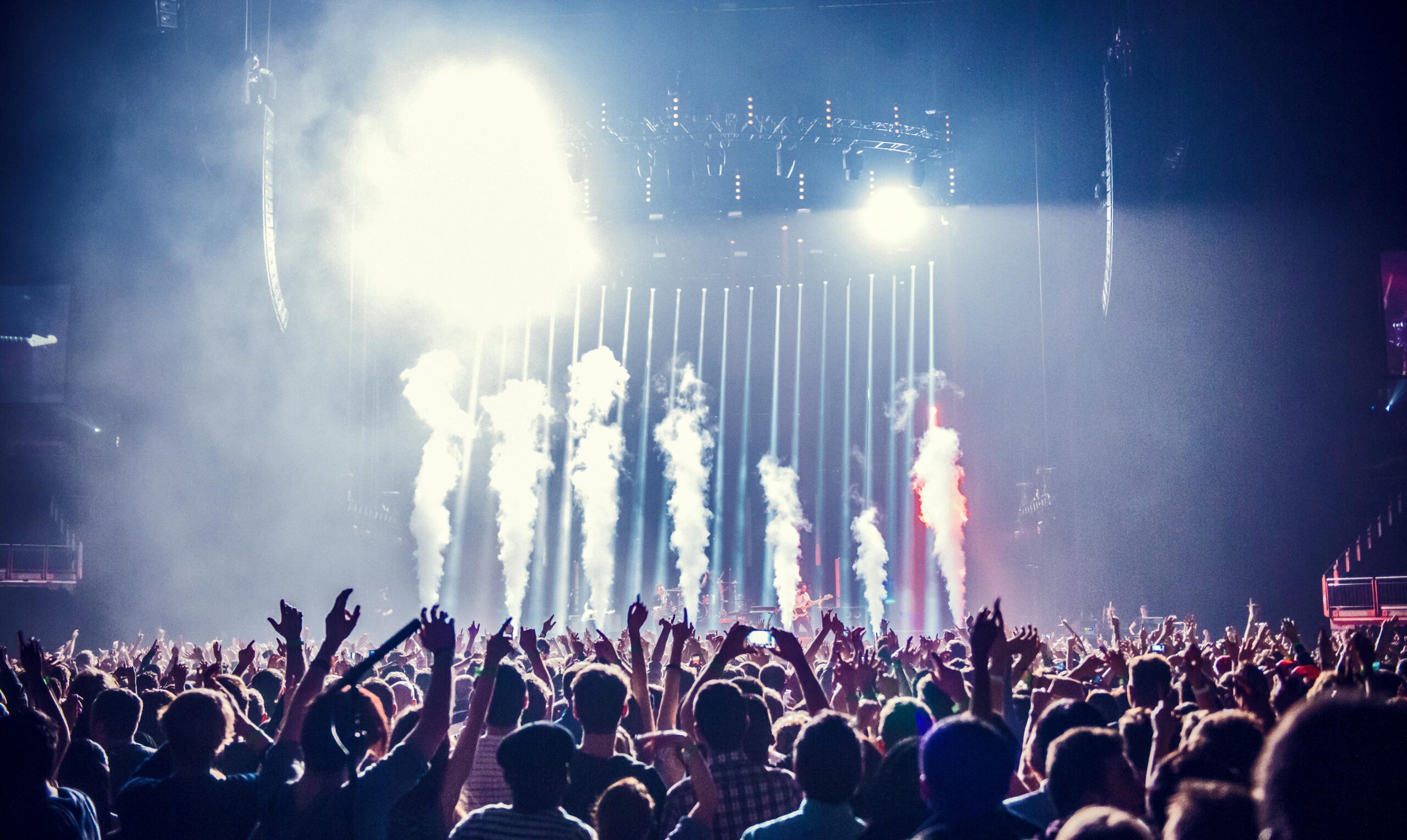 Vibrant concert scene with cheering crowd and bright stage lights creating an electric atmosphere.