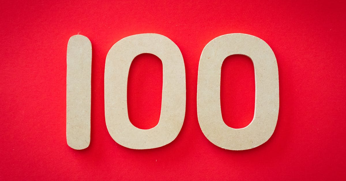 Close-up of numeral 100 in beige on a bright red background, emphasizing celebration.