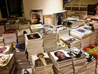 Huge stacks of diverse fashion and lifestyle magazines piled high in an indoor store setting.