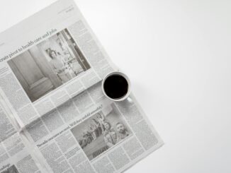 A fresh cup of coffee resting on a newspaper, perfect morning routine setup.