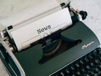 Close-up of an antique typewriter with 'News' on paper.