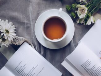 Inviting cozy reading setup with tea, poetry books, and fresh flowers on a table.