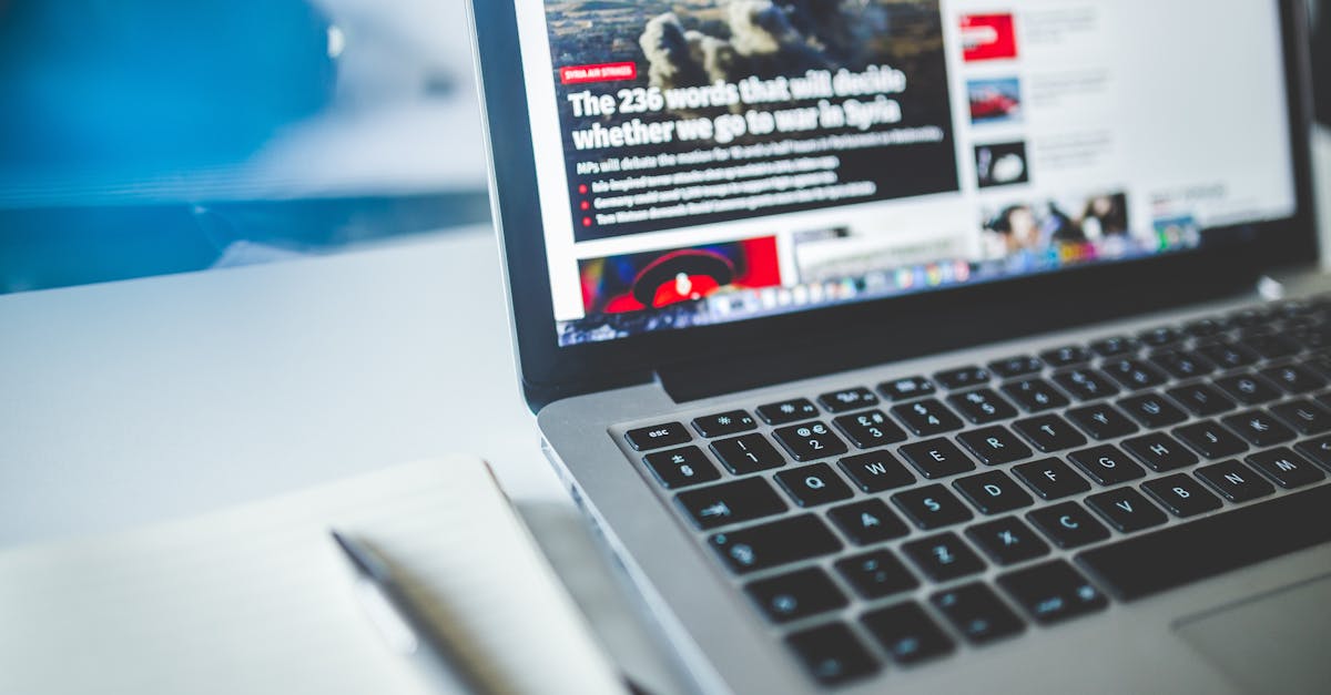 Open laptop displaying an online news article on a desk with a notebook nearby.