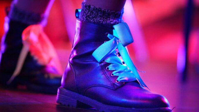 Close-up of stylish leather boots with colorful lighting in an artistic setting.