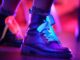 Close-up of stylish leather boots with colorful lighting in an artistic setting.