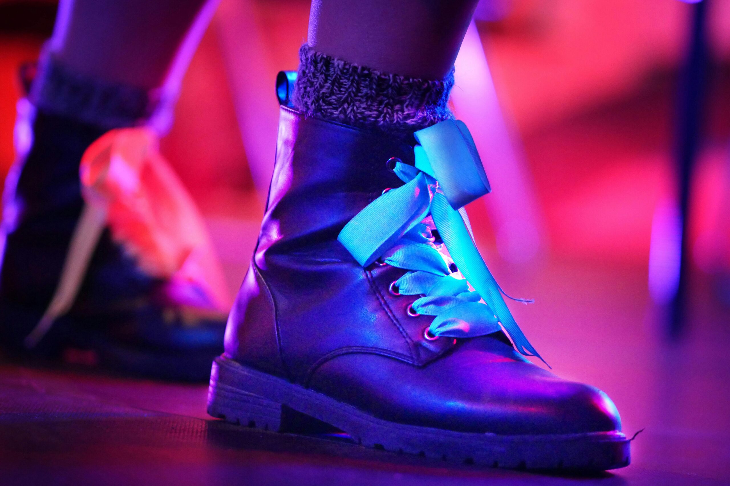 Close-up of stylish leather boots with colorful lighting in an artistic setting.