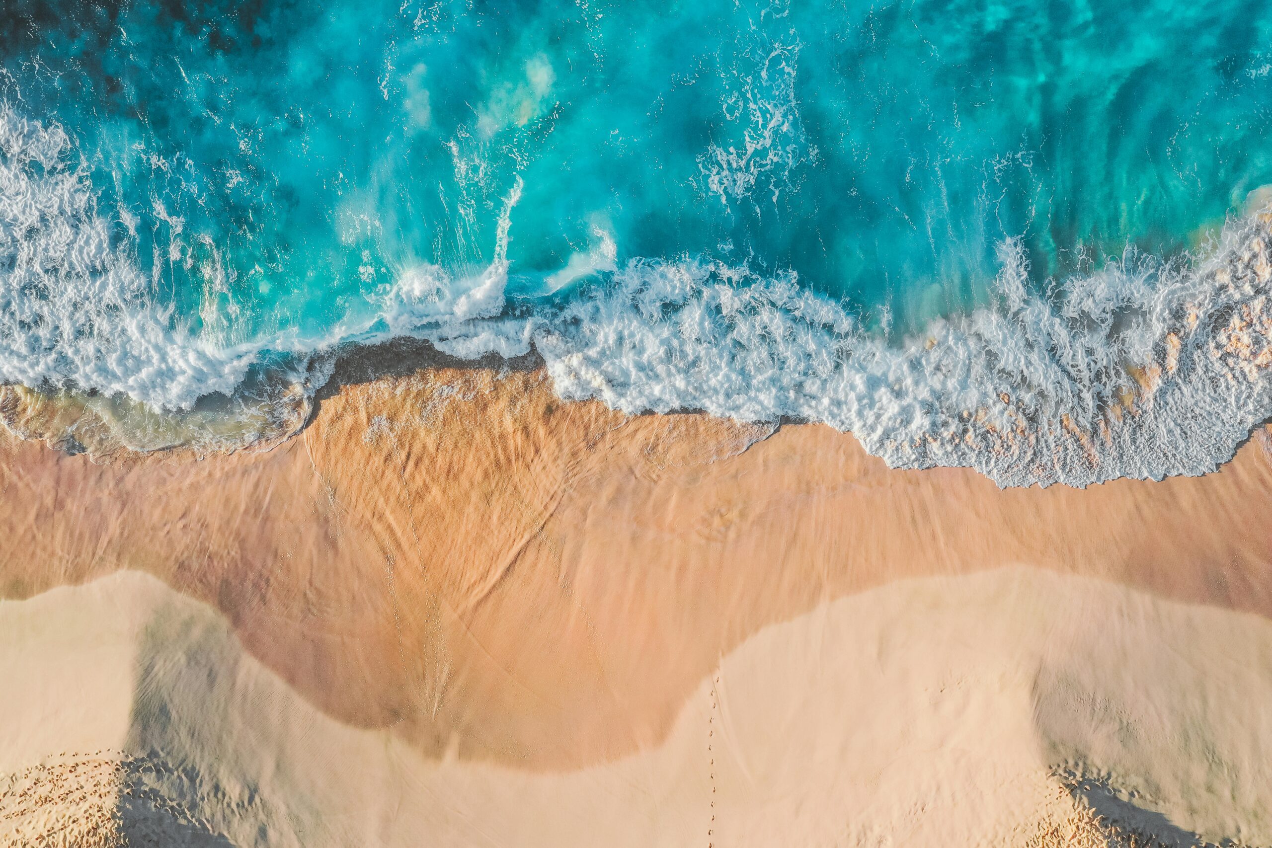 Stunning aerial view of turquoise waves hitting a sandy beach, perfect for nature lovers.