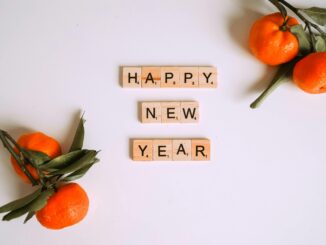 Happy New Year message with Scrabble tiles and fresh mandarins for festive decor.