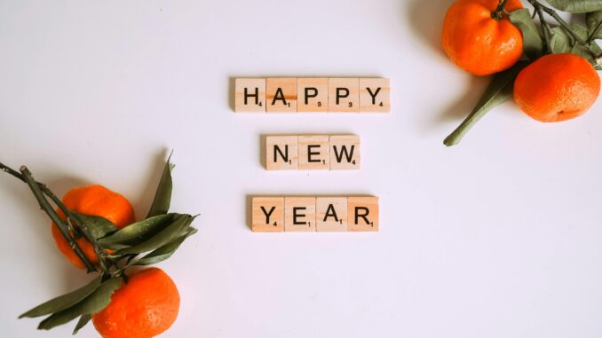 Happy New Year message with Scrabble tiles and fresh mandarins for festive decor.