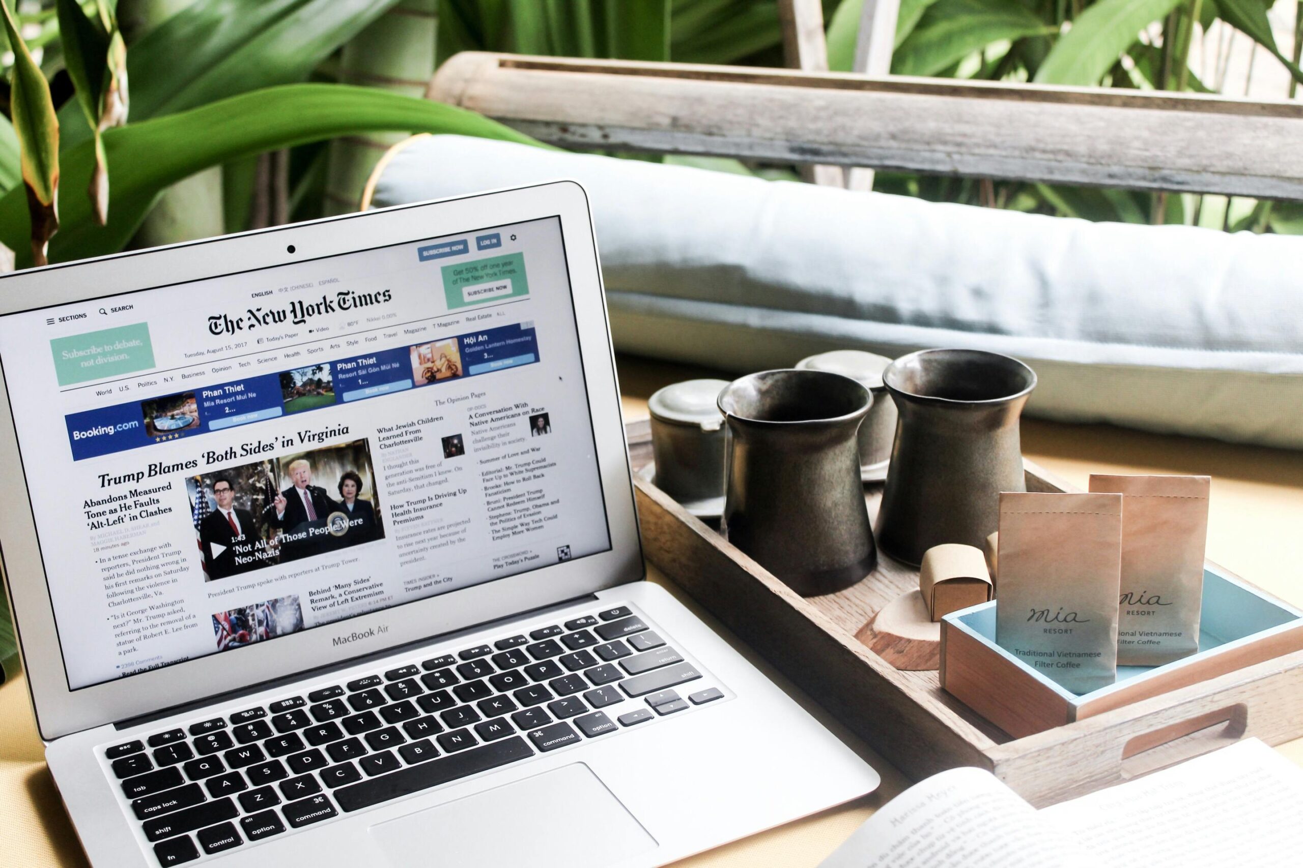 High angle of modern laptop with news on screen placed on table next to tin cups
