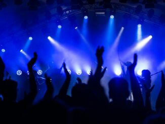 Dynamic concert scene with cheering crowd and vibrant blue lighting.