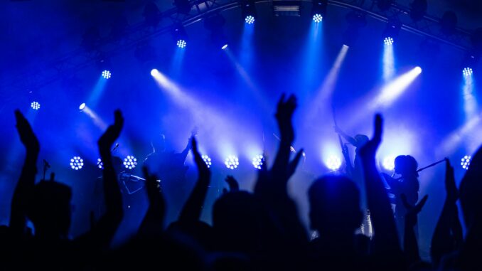 Dynamic concert scene with cheering crowd and vibrant blue lighting.