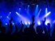 Dynamic concert scene with cheering crowd and vibrant blue lighting.