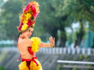 Cheerful woman in vibrant attire dancing at a lively outdoor festival.