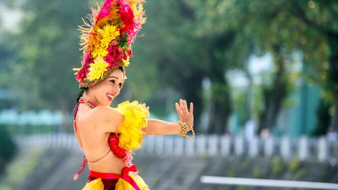 Cheerful woman in vibrant attire dancing at a lively outdoor festival.
