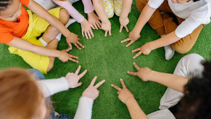 Children sitting in a circle playing fun team games on artificial grass.