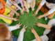 Children sitting in a circle playing fun team games on artificial grass.
