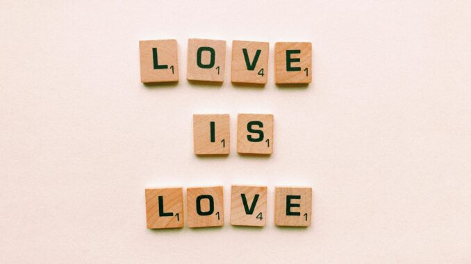 Wooden letter tiles forming 'Love is Love', symbolizing inclusion and pride.