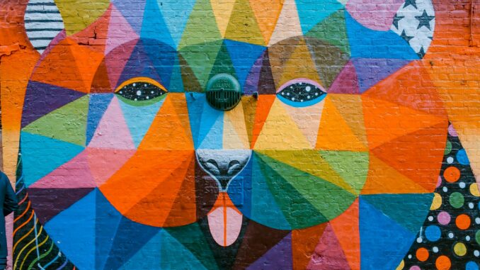 Vibrant geometric mural of a bear on a brick wall in London, showcasing diverse colors and artistic flair.