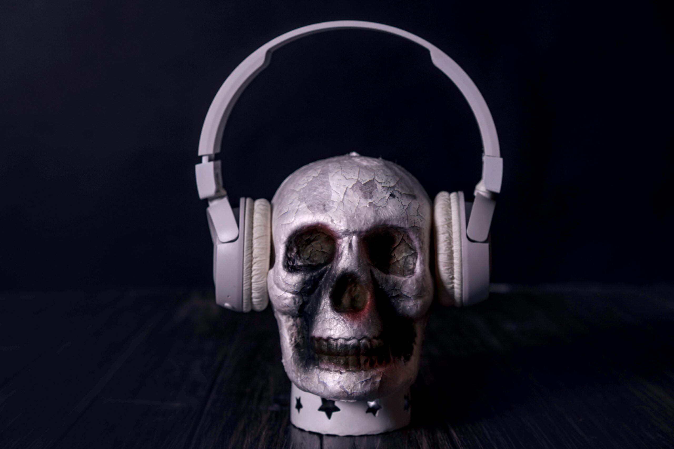 A creepy skull adorned with headphones, casting an eerie vibe against a black background.