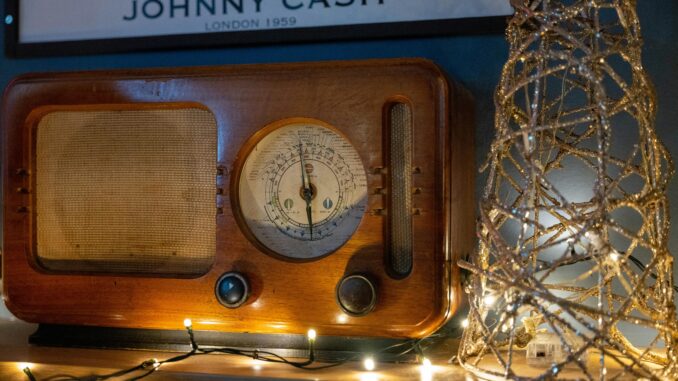 A classic wooden radio adorned with decorative string lights and a retro poster backdrop.
