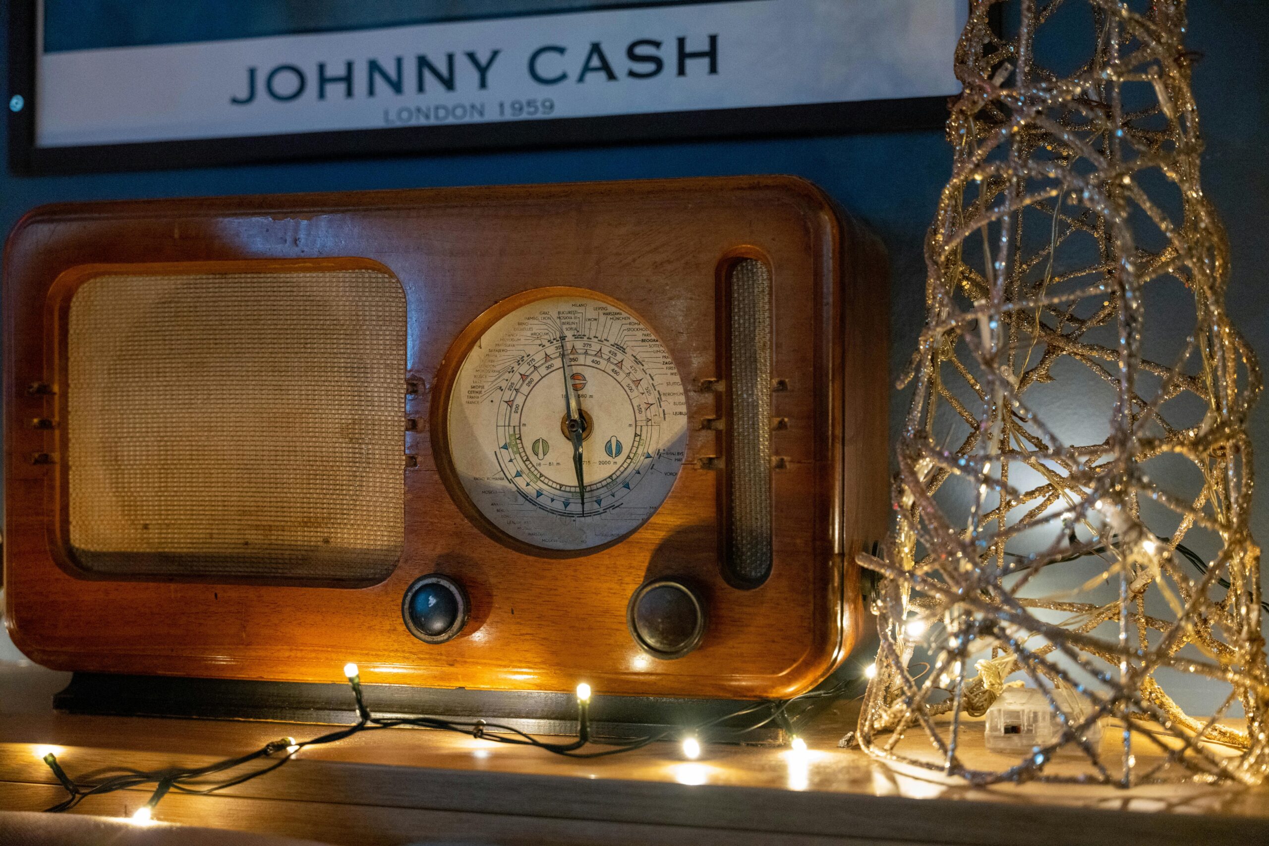A classic wooden radio adorned with decorative string lights and a retro poster backdrop.