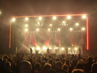 Dynamic live concert with band on stage, lighting effects, and enthusiastic crowd at night.