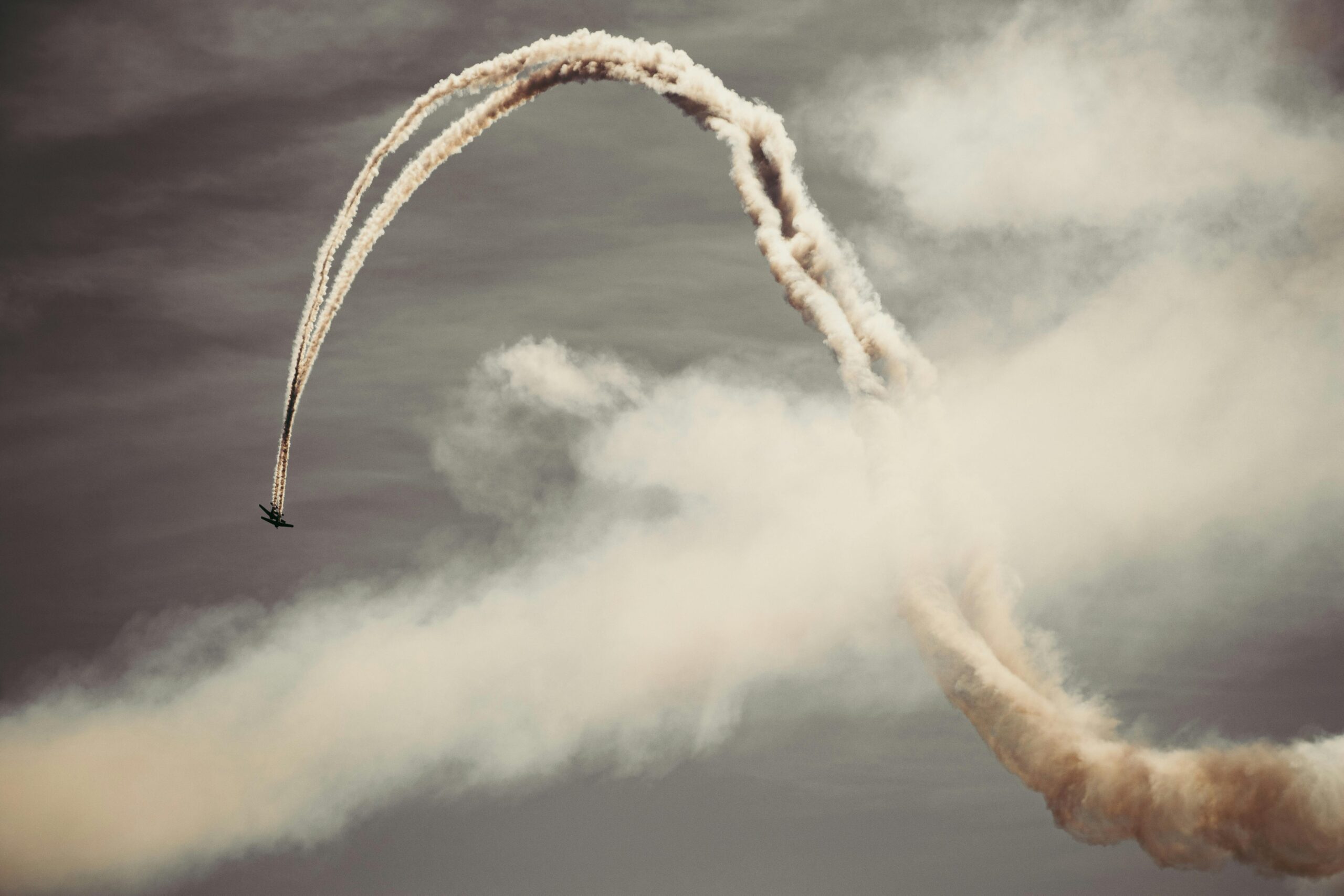 A thrilling airplane performing acrobatics in the sky with smoke trails.