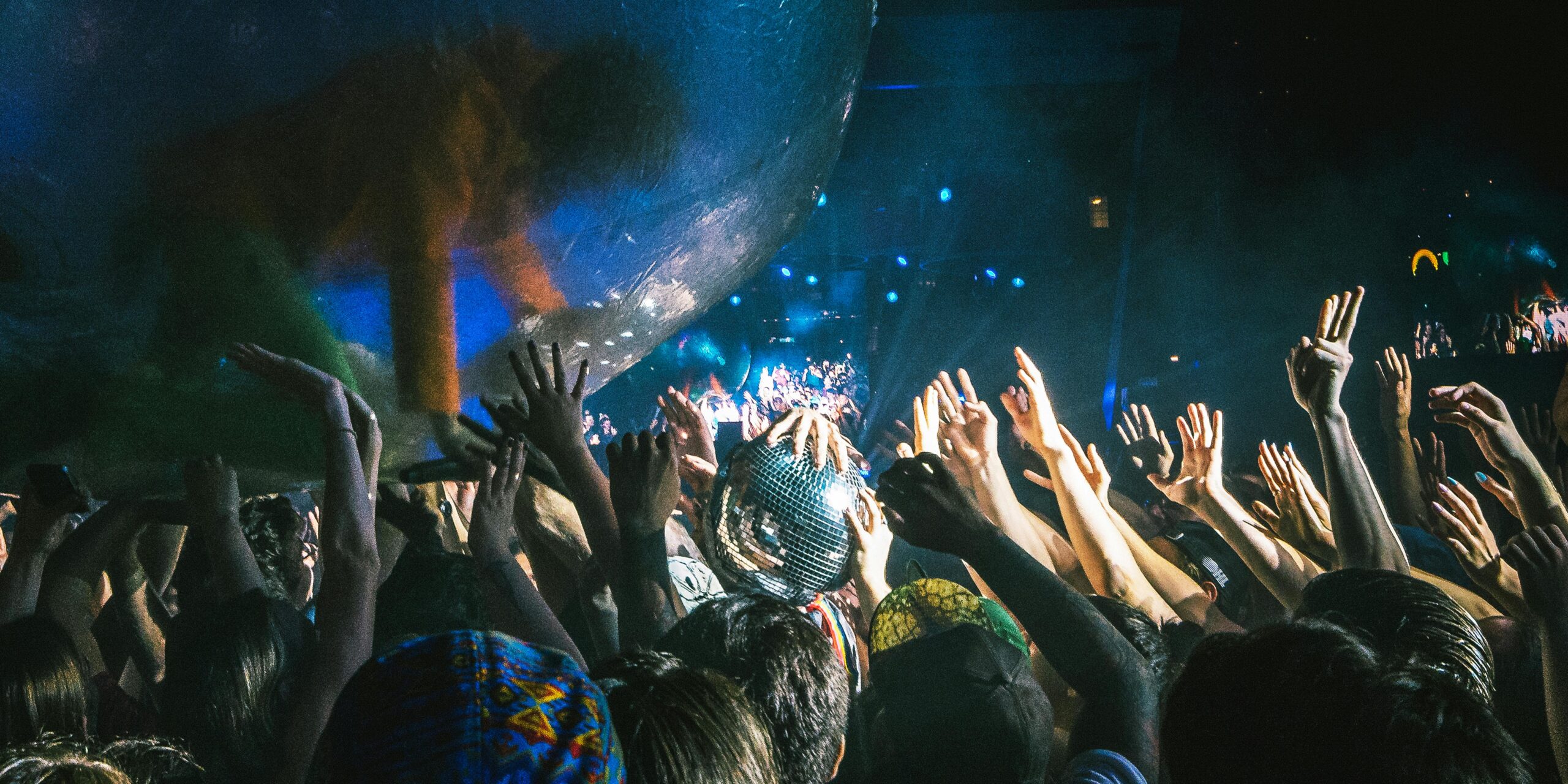 Lively concert scene with excited crowd and performer in a transparent ball at night.