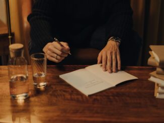 Man signing books during an intimate creative event in a cozy indoor setting.