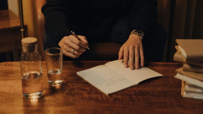 Man signing books during an intimate creative event in a cozy indoor setting.