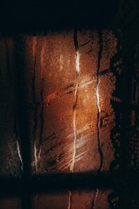 Water drops flowing on misted glass window during rain in cold dark evening