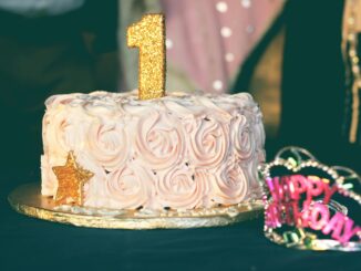 A beautiful first birthday cake adorned with pink rosette frosting and golden decorations. Perfect for celebrations.