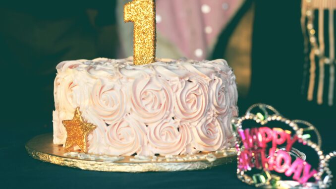 A beautiful first birthday cake adorned with pink rosette frosting and golden decorations. Perfect for celebrations.