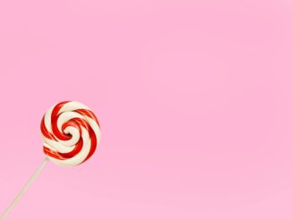 Vibrant red and white lollipop on a pastel pink background, perfect for confectionery themes.
