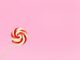 Vibrant red and white lollipop on a pastel pink background, perfect for confectionery themes.