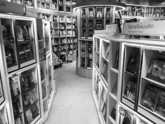 Monochrome view of a bookstore's interior with various bookshelves and romance fiction section.