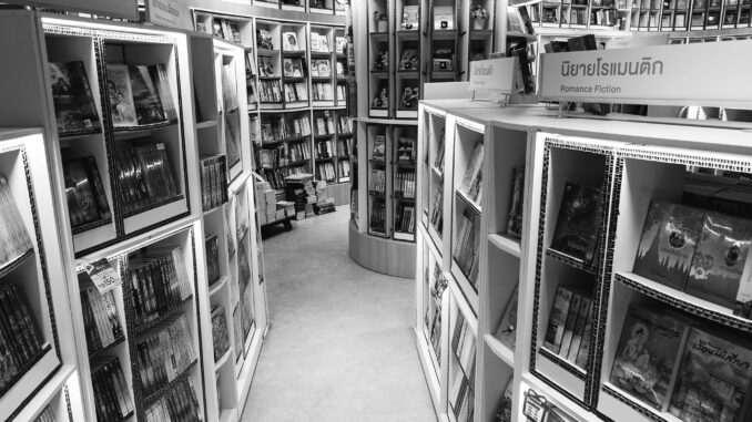 Monochrome view of a bookstore's interior with various bookshelves and romance fiction section.