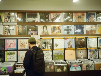 Young man browsing vinyl records in a vintage music store, exploring musical classics.