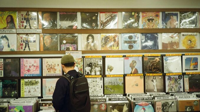 Young man browsing vinyl records in a vintage music store, exploring musical classics.